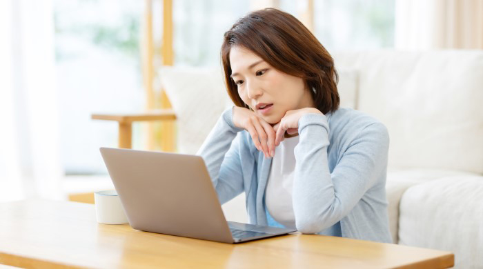 PCを見て悩む女性