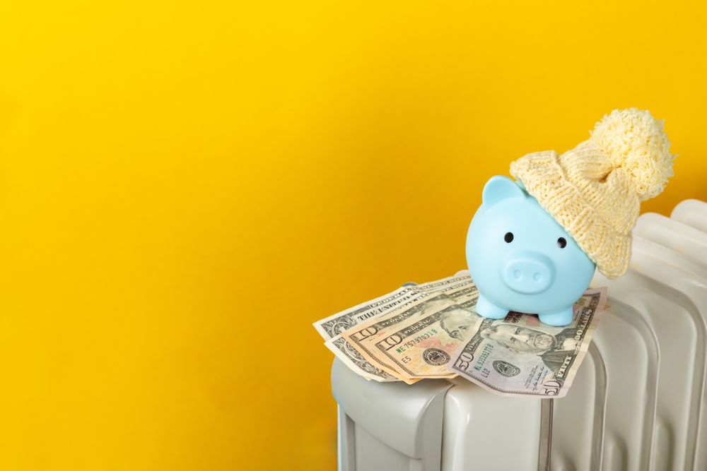 暖房器具の上にお金とブタの貯金箱
