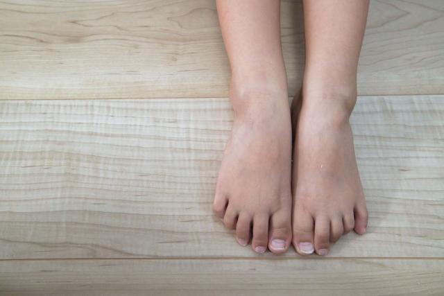 木目調のフローリングの上に、素足を揃えて置いている様子。